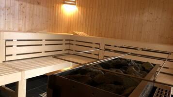 Een sauna met houten banken, een verwarmde stenen vloer en een schuin dak.