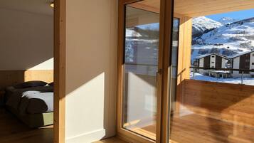 A room with a large sliding glass door leading to a balcony with a mountain view.