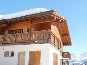 A wooden chalet with a balcony, white walls, and a mountain backdrop. - Casa Mulinera 2 Derycke, (Camischolas/Sedrun), 243.02 by Interhome (Camischolas)