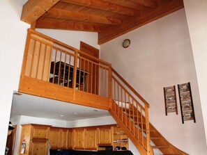 A wooden staircase leading to an upper floor with a kitchen area below. - Casa Mulinera 2 Derycke, (Camischolas/Sedrun), 243.02 by Interhome (Camischolas)