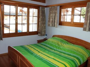 A room with a bed, wooden headboard, and a window with curtains. - Casa Mulinera 2 Derycke, (Camischolas/Sedrun), 243.02 by Interhome (Camischolas)