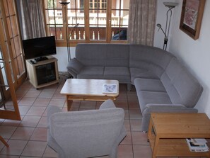 A living room with a grey sofa, a wooden coffee table, a TV stand, and a floor lamp. - Casa Mulinera 2 Derycke, (Camischolas/Sedrun), 243.02 by Interhome (Camischolas)