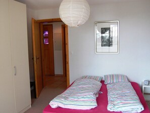 A bedroom with a bed, a door, a window, and a wall-mounted picture. - Londadusa OG, (Rueras/Sedrun), 178.01 by Interhome (Rueras Dieni)