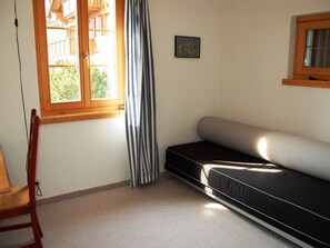 Una habitación con un sofá negro, una ventana con marcos de madera, una cortina a rayas y un cuadro de cebra en la pared.