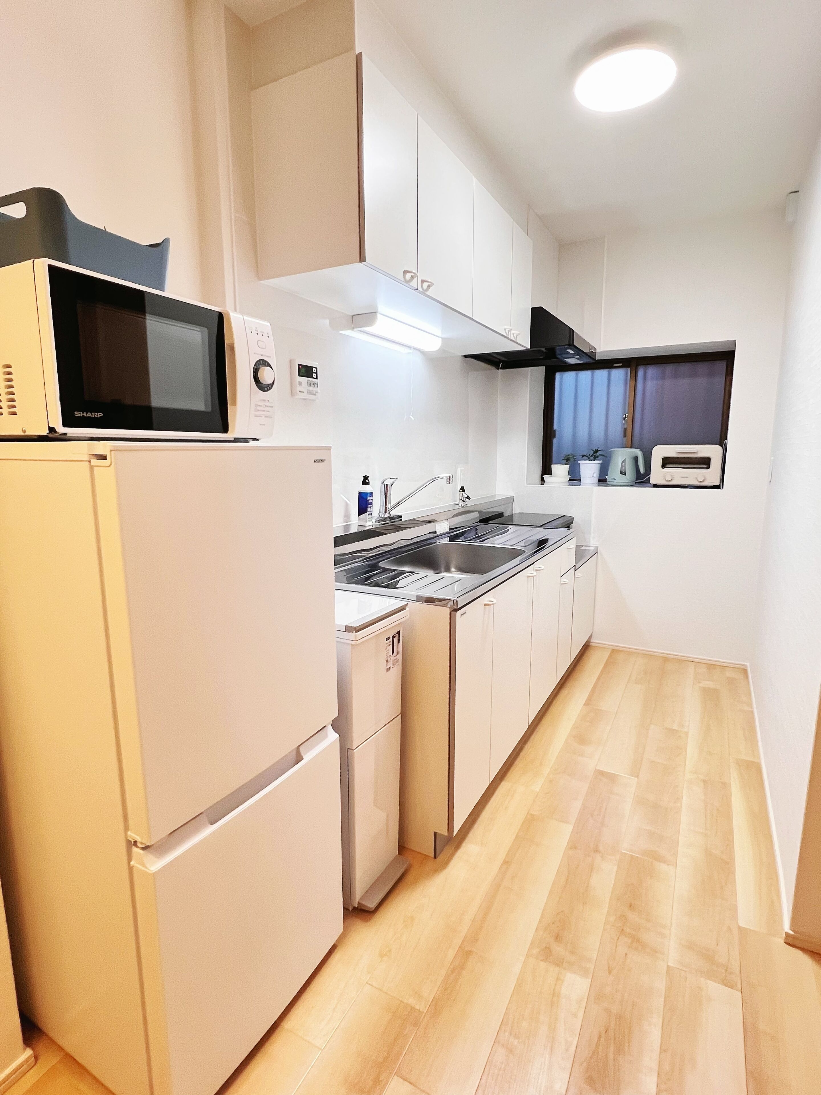 A compact kitchen with a microwave, stove, sink, and a toaster.