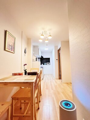 A narrow hallway with a dining area featuring a wooden table and chairs, a kitchen in the background, and a ceiling light fixture. - 4min walk JR Kyobashi · Entire home · 7guests · Renovated · Walk to Osaka Castle (大阪市)