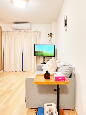 A living room with a sofa, a TV, a tray table, a vase, and a box on the floor. - 4min walk JR Kyobashi · Entire home · 7guests · Renovated · Walk to Osaka Castle (大阪市)