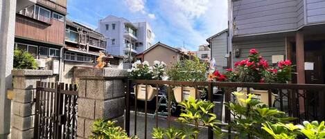 A residential area with a gated entrance, a small garden with potted plants, and a clear blue sky.