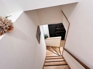 A staircase leading to a room with a dark wooden door, a framed picture on the wall, and a potted plant. - 4min walk JR Kyobashi · Entire home · 7guests · Renovated · Walk to Osaka Castle (大阪市)