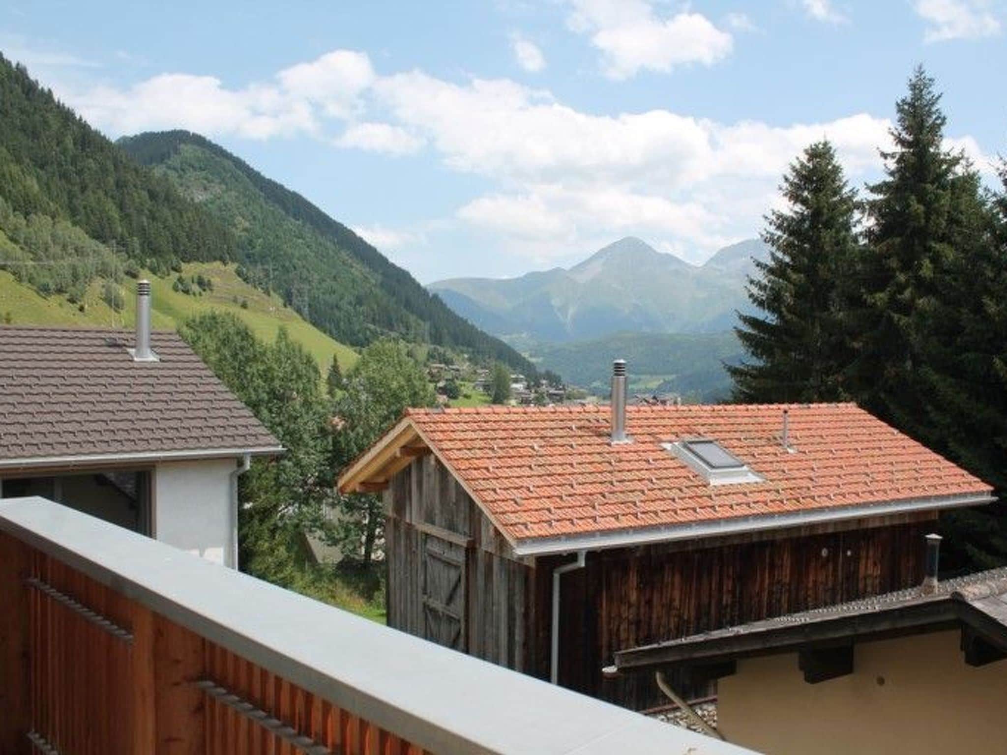 Eine Berglandschaft mit einem Holzbauten und einem modernen Gebäude mit Ziegeldach.