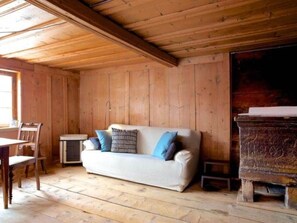 A wooden interior with a white sofa, blue cushions, a small table, and a fireplace. - Tgèsa Surrein Giassa10, (Sedrun/Surrein), 602.01 by Interhome (Sedrun)
