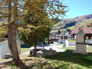 A rural village with traditional houses, a large coniferous tree, and a stone monument. - Londadusa Parterre, (Rueras/Sedrun), 178.02 by Interhome (Rueras Dieni)