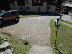 A paved driveway leading to a building with a stone facade and a parked car. - Londadusa Parterre, (Rueras/Sedrun), 178.02 by Interhome (Rueras Dieni)