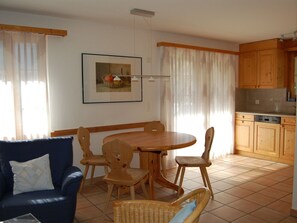 Un comedor con una mesa y sillas de madera, un sofá y una cocina con armarios de madera.