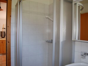 Un baño con ducha, lavamanos y espejo.