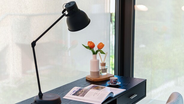 A desk with a lamp, a vase with flowers, a cup, and a magazine. - Villa Violetta (Menaggio)