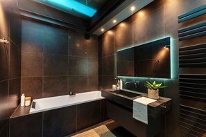Een moderne badkamer met een badkuip, een wastafel en een grote spiegel.