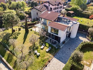 A modern two-story house with a flat roof, large windows, and a spacious patio area. - Villa Violetta (Menaggio)