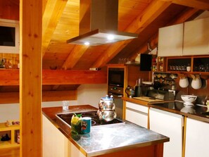 A kitchen with wooden beams, a stove, a kettle, and various kitchen utensils. - Haus Polishet, (Sedrun), 179.06 by Interhome (Sedrun)