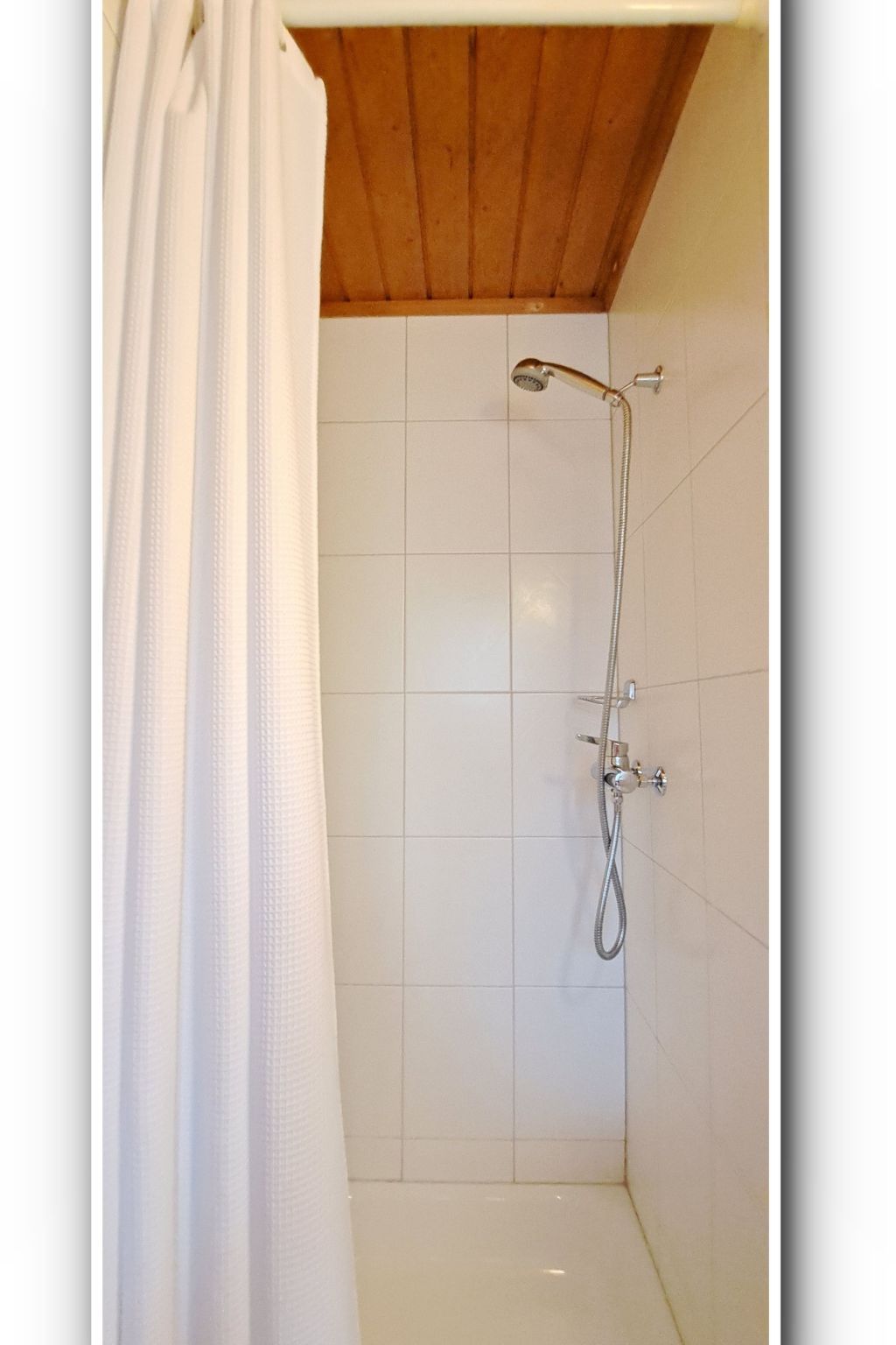 Ducha con cabezal de ducha de mano y grifo instalado en la pared.