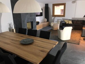 A modern living room with a wooden dining table, black chairs, a sofa, and a television mounted on the wall. - CATRINA RESORT, (Disentis / Mustér), 2010 by Interhome (Disentis)