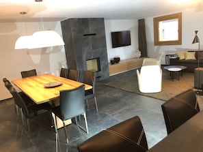 Ein modernes Wohnzimmer mit Essbereich, Kamin und flachbildschirm am Wand.