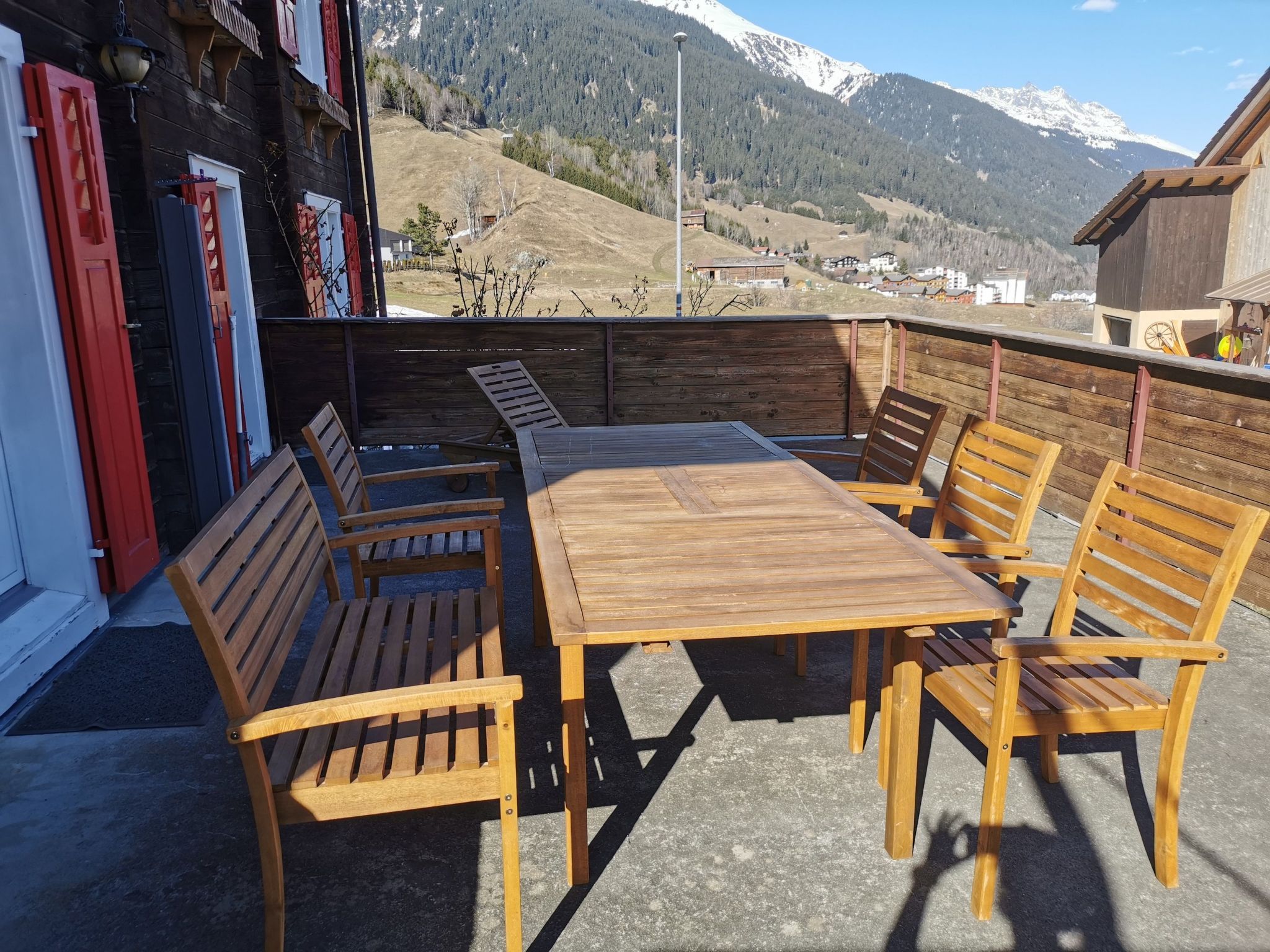 An outdoor wooden deck with a table and benches, overlooking a mountainous landscape.