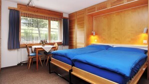 Une chambre avec un lit, un bureau et une fenêtre avec des rideaux.