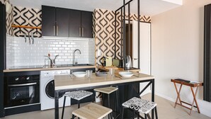 Een moderne keuken met een centraal eiland, een zwart-wit betegelde spatwand en een houten aanrechtblad.