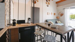 Een moderne keuken met een houten aanrecht, zwarte kastjes en een eethoek met een tafel en stoelen.