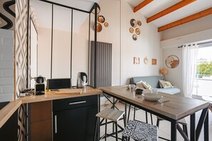 A modern kitchen with a wooden countertop, black cabinets, and a dining area with a table and chairs. - La Parenthèse Rochelaise (with Parking Space) by Kaz'Concept (La Rochelle)