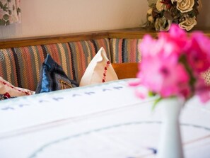 A bed with a striped headboard, a white pillow, and a vase with pink flowers. - Cuntera Venzin, (Curaglia), 5002 by Interhome (Baselgia)