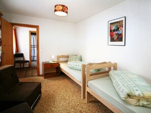 A small, cozy room with two wooden beds, a desk, a chair, and a single hanging light fixture. - Ferienwohung Cavegn-Cavigelli, (Sedrun), 129.01 by Interhome (Sedrun)