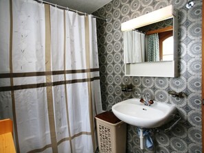 A bathroom with a shower curtain, a sink, and a mirror. - Ferienwohung Cavegn-Cavigelli, (Sedrun), 129.01 by Interhome (Sedrun)
