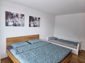 A bedroom with a wooden bed, a smaller bed, and two abstract paintings on the wall. - Ladina, (Disentis/Mustér), 1724 by Interhome (Disentis)