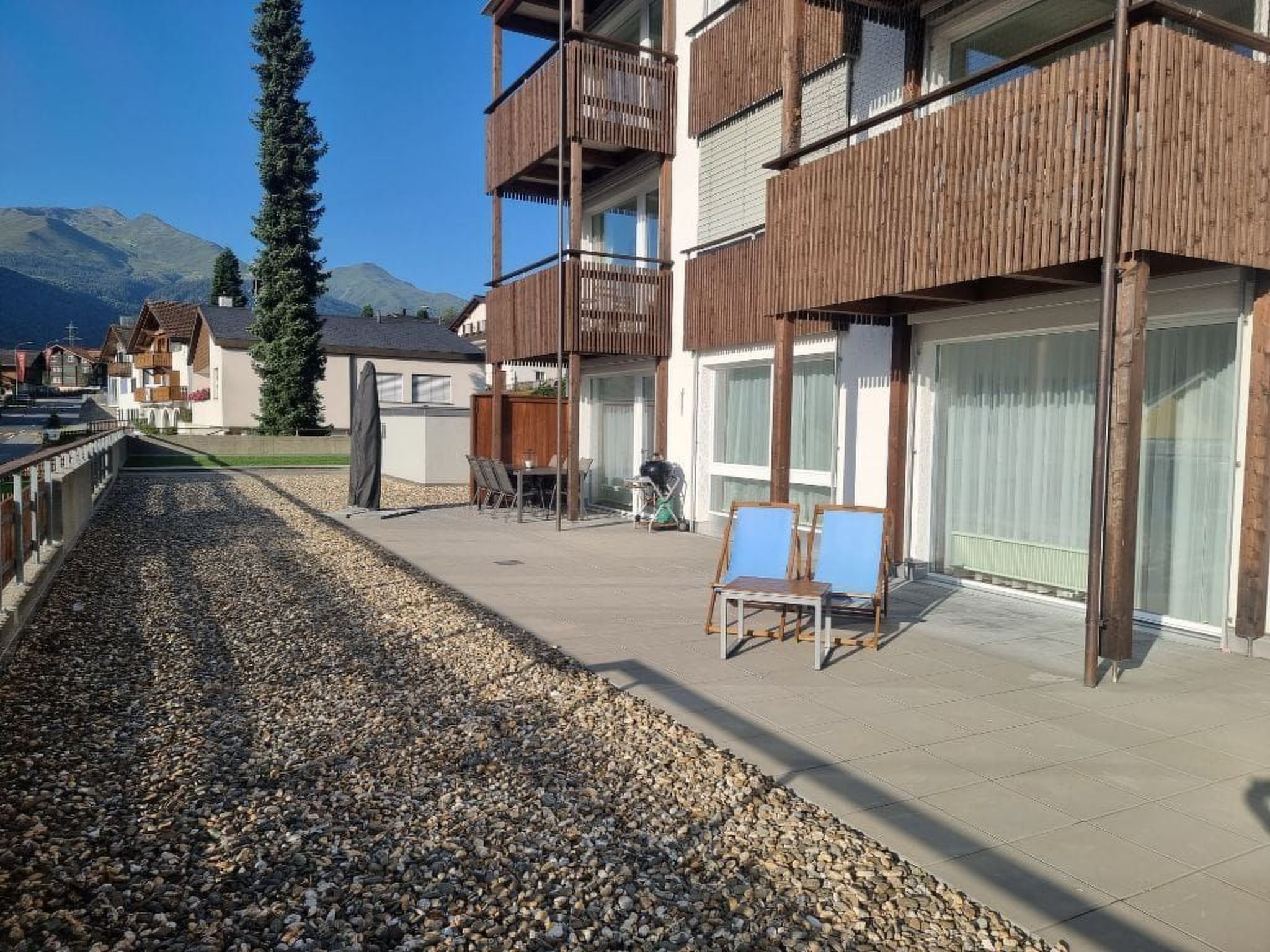 A residential building with a balcony, a grill, and a view of mountains.