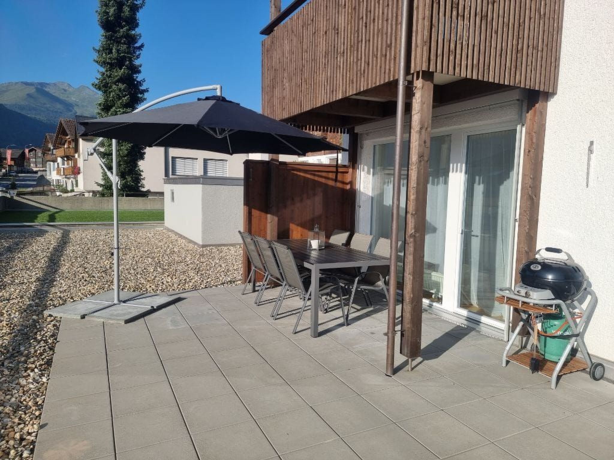 Une terrasse extérieure avec une table et des chaises, un barbecue et une plateforme en bois.