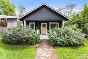A house with a stone pathway leading to the front door, surrounded by well-maintained shrubs and a clear sky. - Designer 4BR Near Downtown Austin (Austin)