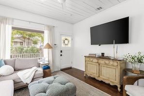 A living room with a sofa, ottoman, TV, and a cabinet. - Designer 4BR Near Downtown Austin (Austin)