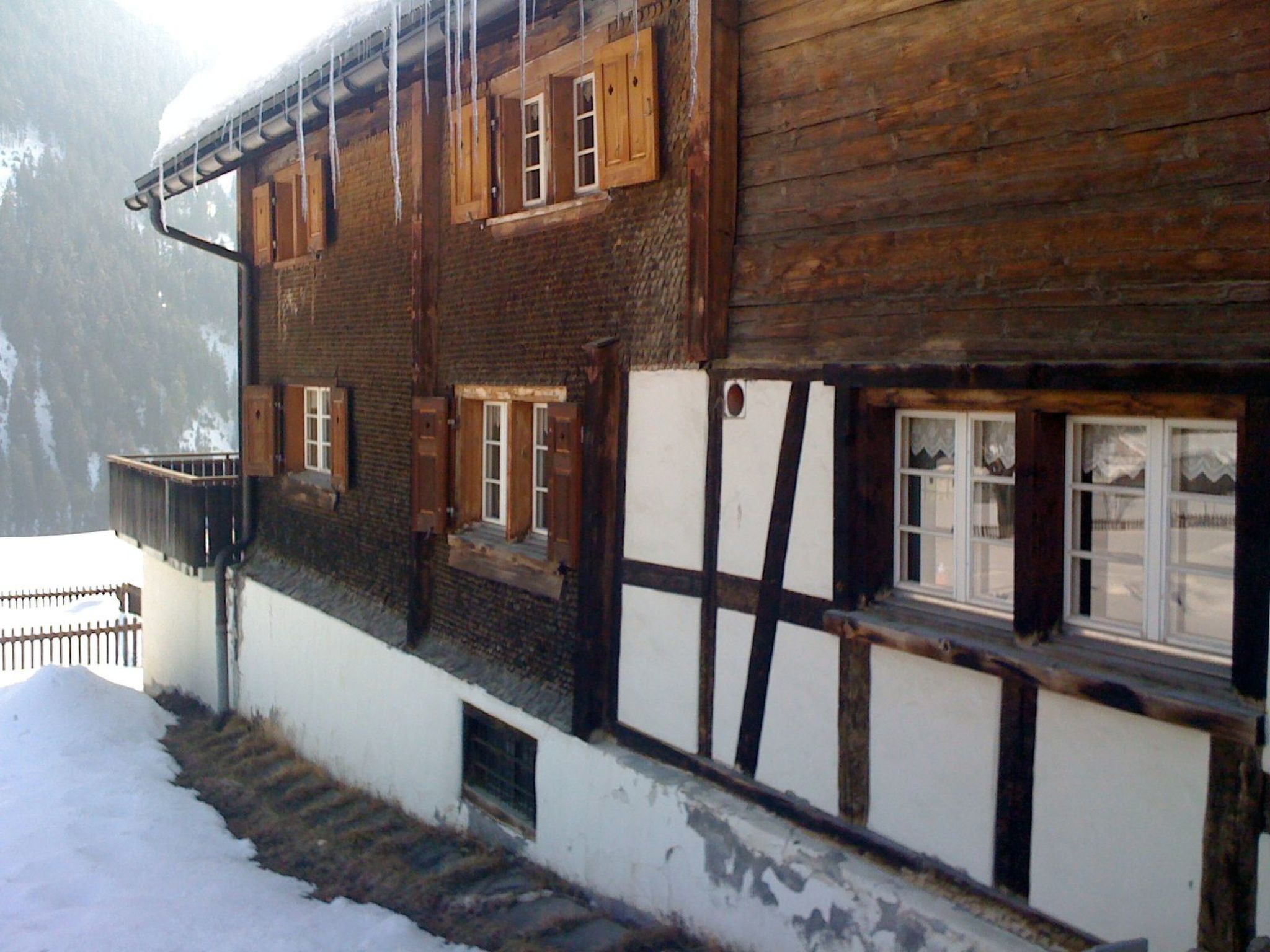 A traditional wooden building with multiple windows and a staircase leading to a lower level.
