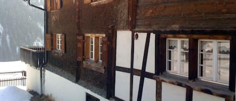 A traditional wooden building with multiple windows and a staircase leading to a lower level.