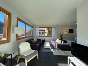A modern living room with a sofa, armchair, and a flat-screen TV. - Dentervitgs, (Sedrun), by Interhome (Sedrun)