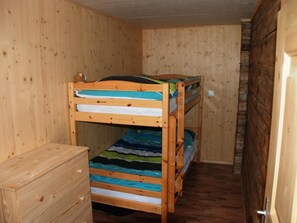 Ein Schlafraum mit Etagenbetten, Holzwänden und einem hölzernen Schminktisch.