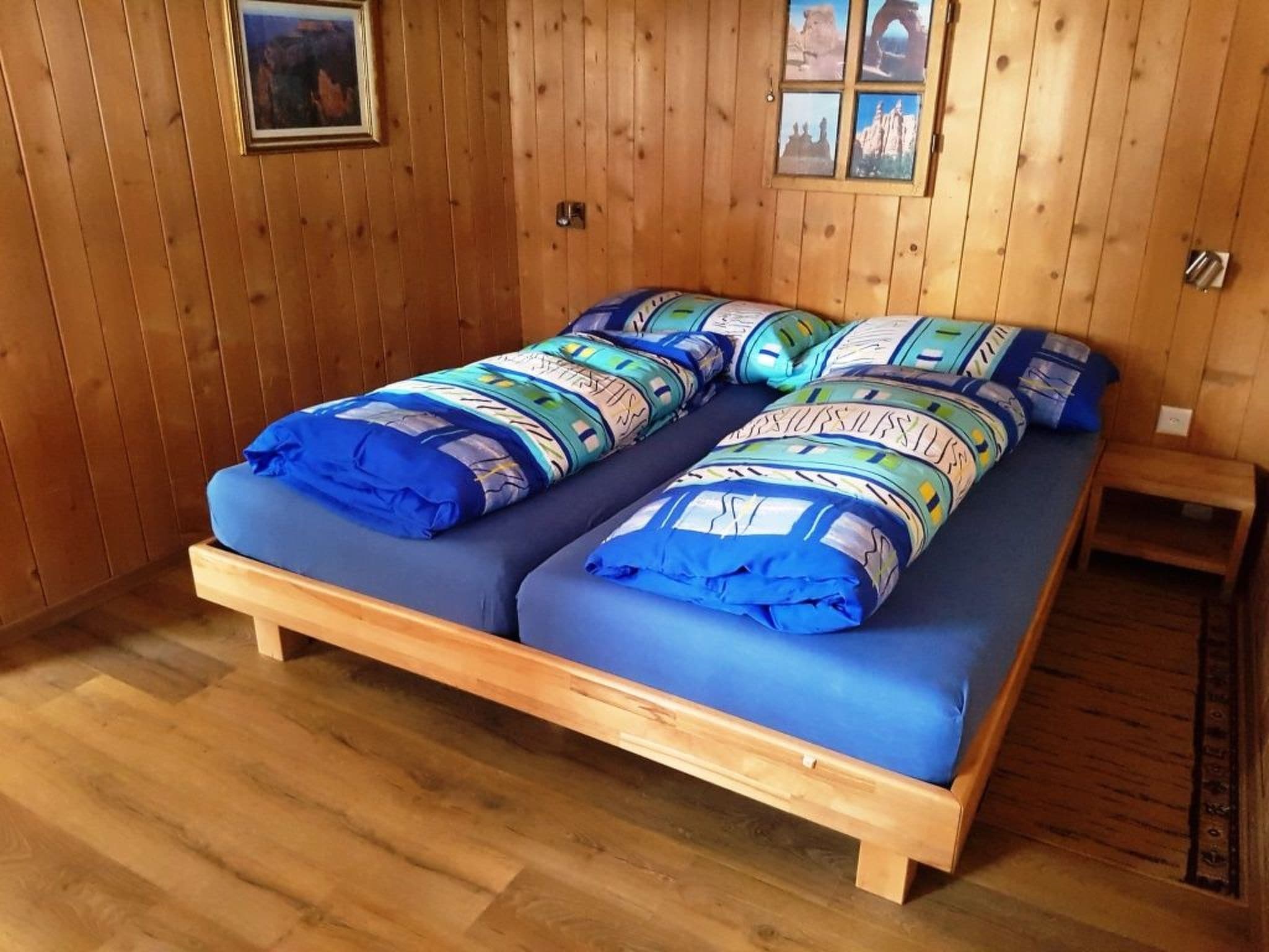 Une pièce en bois avec un lit doté de draps bleus et d’une tête de lit en bois.