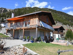 A wooden chalet with a balcony, solar panels, and a stone wall. - Tgèsa Pazzola Huonder-Monn, (Bugnei/Sedrun), 005.01 by Interhome (Sedrun)