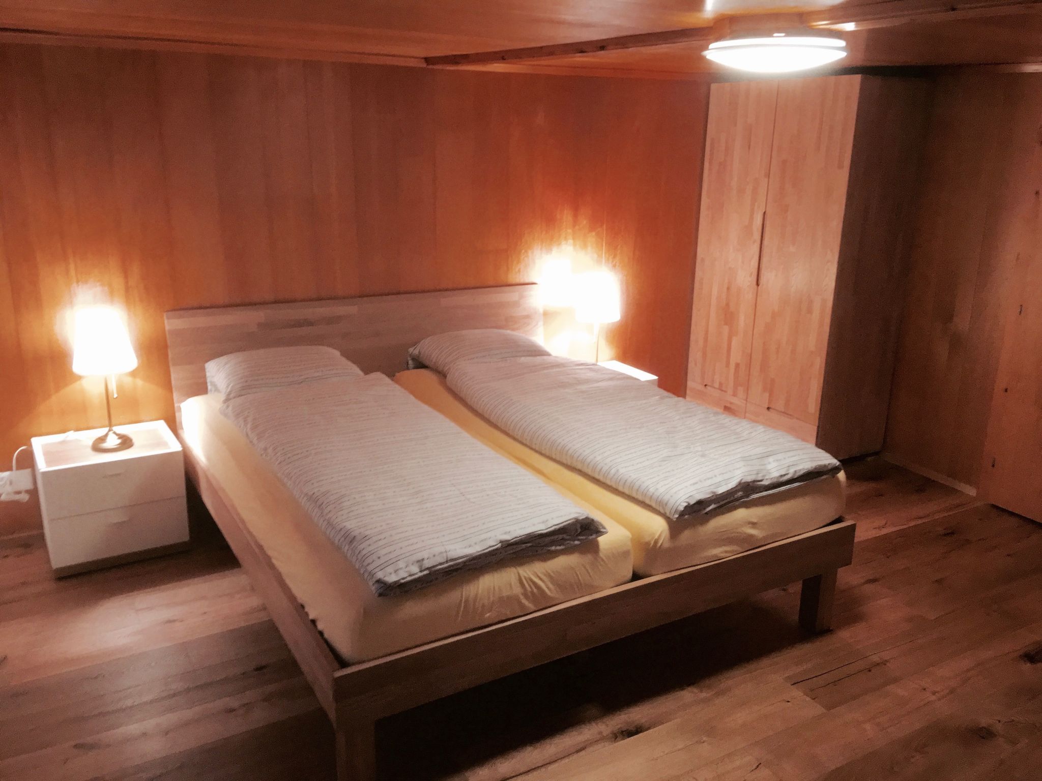 A wooden bed with two bedside tables, each with a lamp.