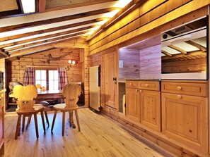 A wooden interior with a dining area, wooden cabinets, and a built-in microwave. - Chalet Dargun Bünter, (Camischolas/Sedrun), 221./222./224./.01+.02+.03 by Interhome (Camischolas)