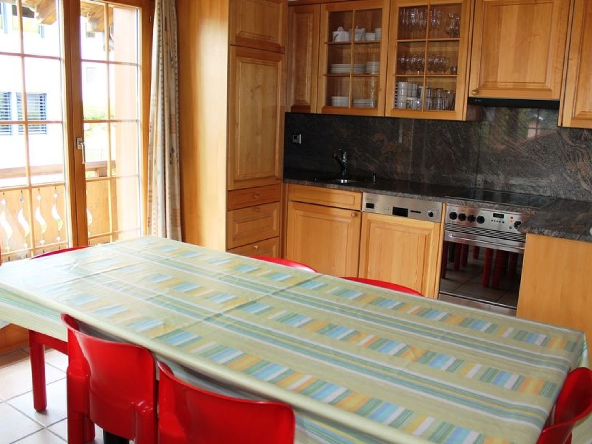 Een keuken met houten kastjes, een zwarte koelkast, een fornuis en een tafel met stoelen.