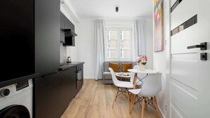 Une cuisine compacte dotée d’appareils électroménagers modernes, un coin repas avec une table et des chaises, et un canapé.