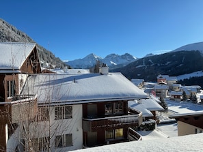A snow-covered mountain village with traditional wooden houses, a clear blue sky, and a view of snow-capped peaks in the background. - Casa Tresch Sedrun, (Tavetsch), by Interhome (Sedrun)